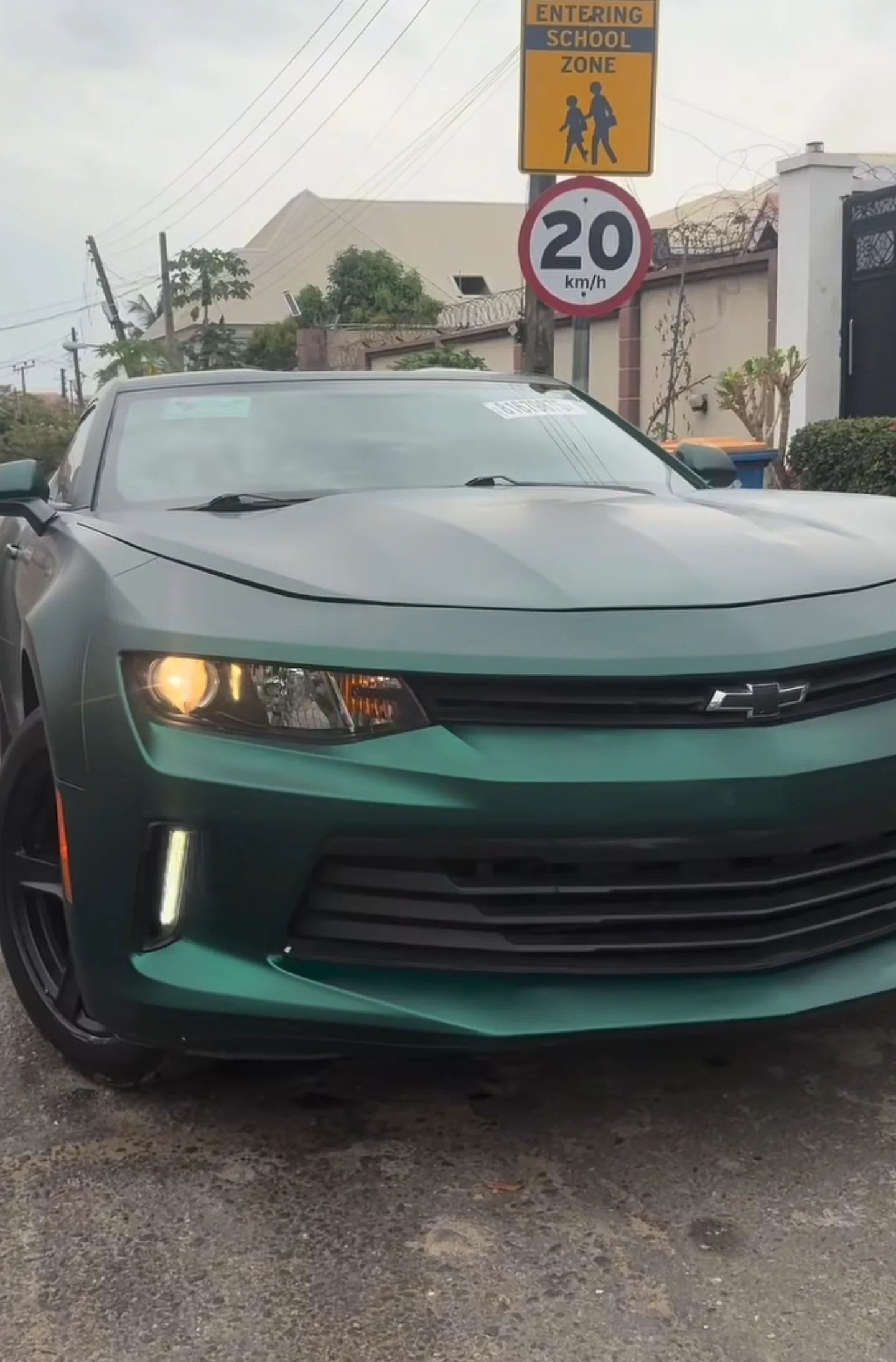 Chevrolet Camaro matte dark green wrap front view complete on Lagos street