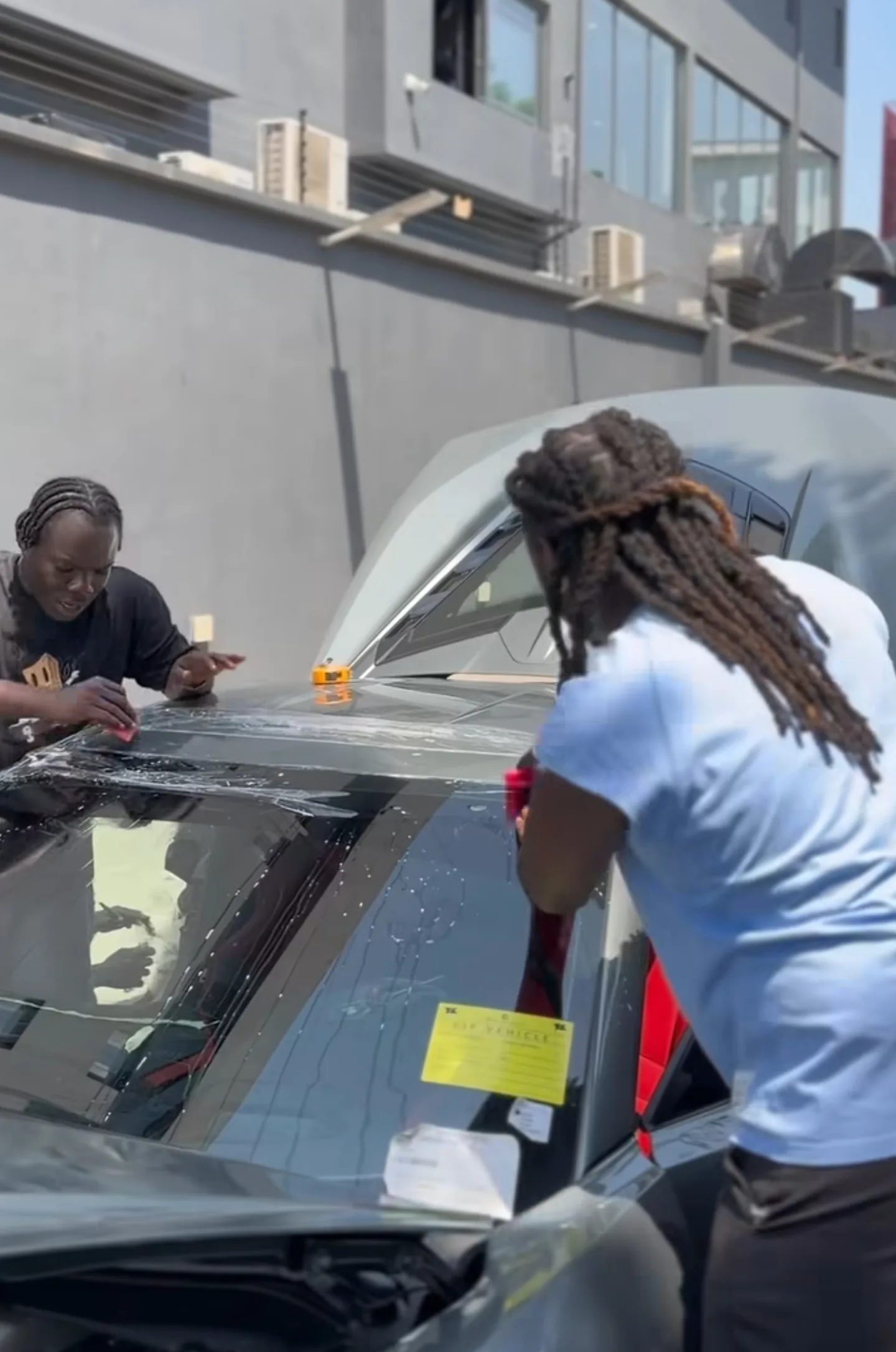 Two technicians applying PPF to Corvette C8 roof panel with squeegee Mohammed Lexus Lagos