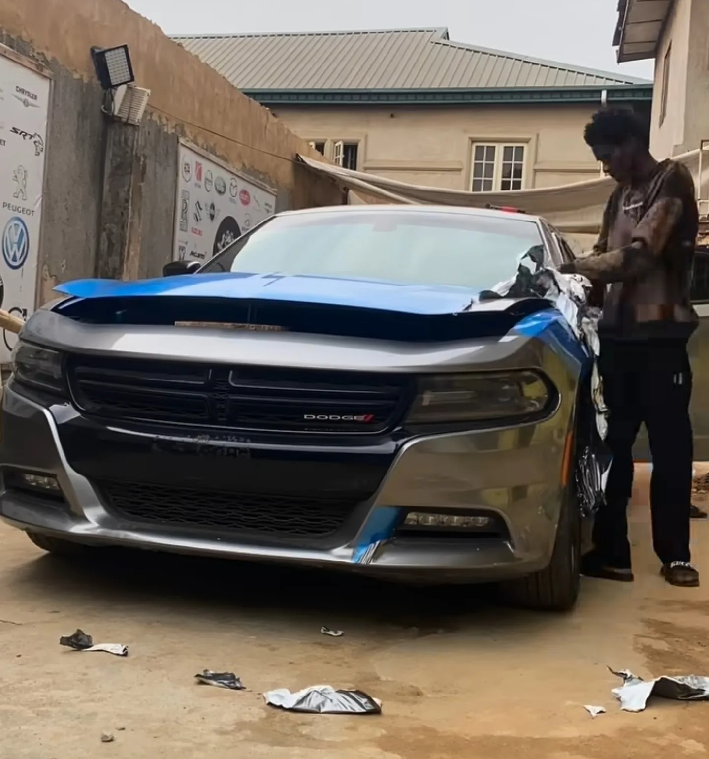Mohammed Lexus technician peeling old silver wrap from the Dodge Charger showing undamaged original paint