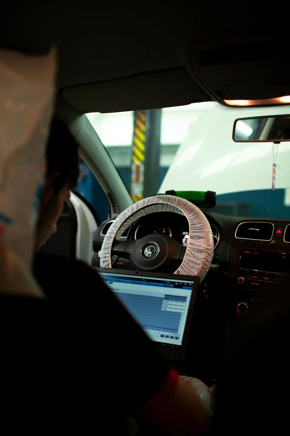 Mechanic with laptop connected to car OBD port ECU tuning diagnostic workshop