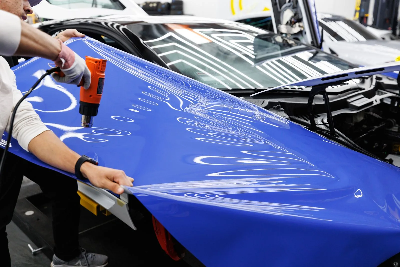 Professional vinyl wrap installation technician applying vinyl to car door panel