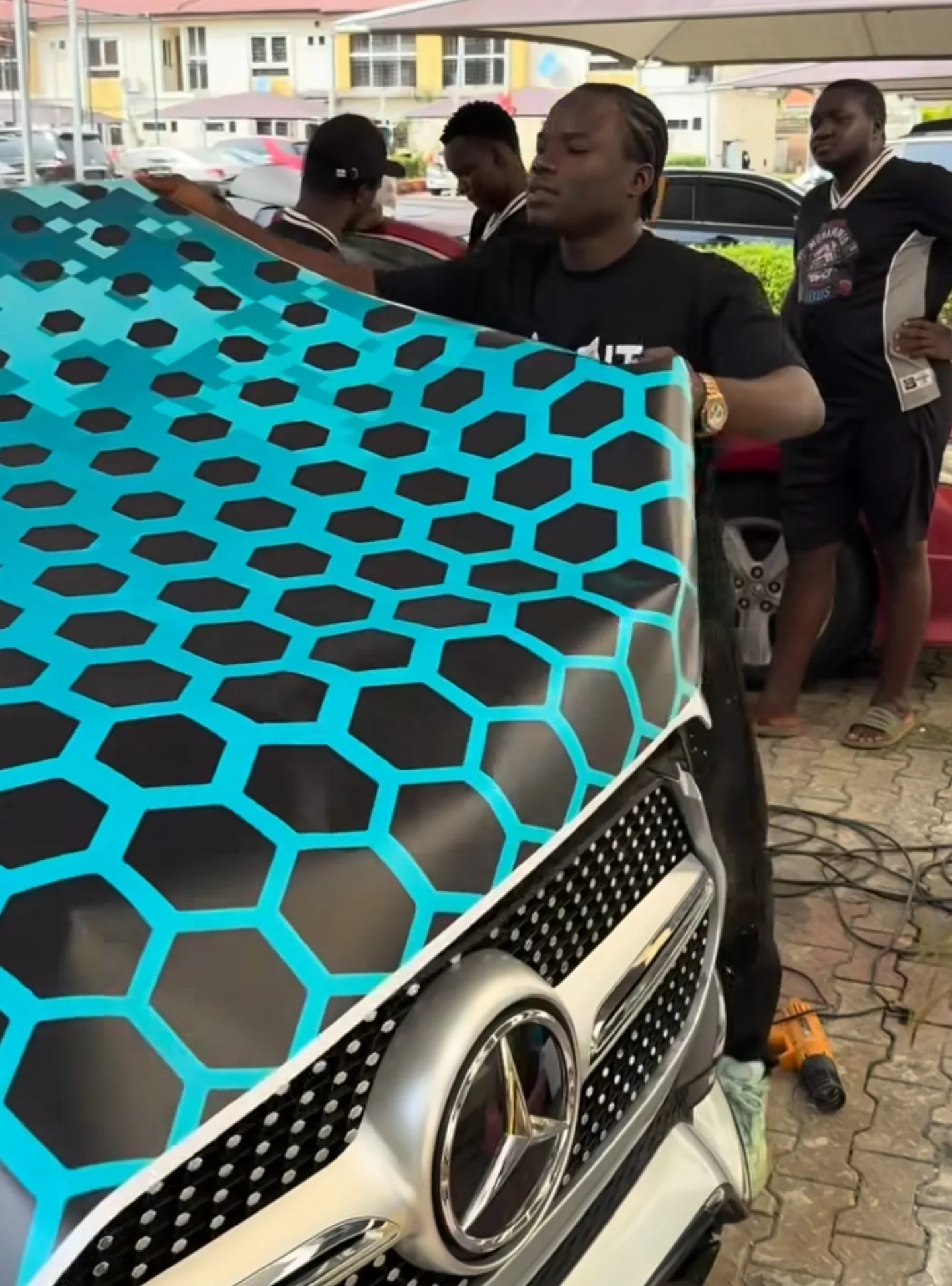 Mohammed Lexus team applying custom teal honeycomb wrap to GLE bonnet installation process